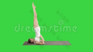 女子练习瑜伽，站在萨拉姆巴沙文加萨纳锻炼，支持肩膀站在绿色屏幕上的姿势